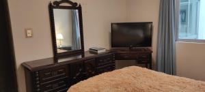 een slaapkamer met een dressoir met een spiegel en een televisie bij San Borja Habitación amoblada TV 42 OK in Lima