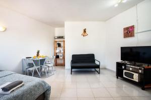 sala de estar con TV y mesa con silla en VILAMOURA MARINA C.A. APARTMENTS, en Vilamoura