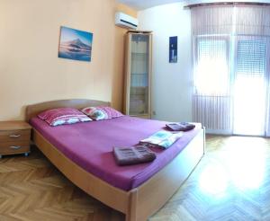 sypialnia z dużym łóżkiem z fioletową pościelą w obiekcie Eros Rooms w Splicie