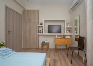 een slaapkamer met een bed, een bureau en een televisie bij Cosy Apartment With Terrace Near Metro Station in Athene