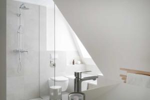 ein weißes Badezimmer mit Dusche und Toilette in der Unterkunft KOSI am Meer ZEHN in Ostseebad Koserow
