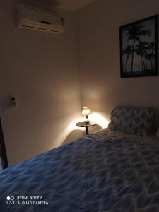 Maxaranguape的住宿－PARAÍSO DE MARACAJAÚ - BEIRA MAR，一间卧室配有一张床和一张带台灯的桌子