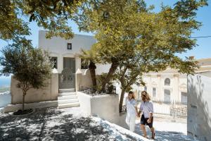 two women walking in front of a white house at Kastro Mansion in Pyrgos