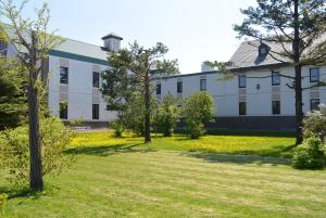 a large white building with trees in the yard at SPA&HOTEL RESORT Furano La Terre in Nakafurano
