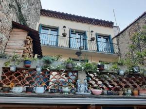 a building with a bunch of potted plants on a ledge at Les Chambres Chouettes in Villefranche-de-Conflent