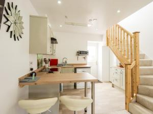 a kitchen with a wooden table and some stairs at Story Cottage in Wigtown