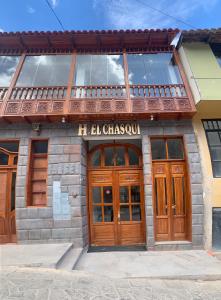 een gebouw met houten deuren en een bord erop bij El Chasqui in Ollantaytambo