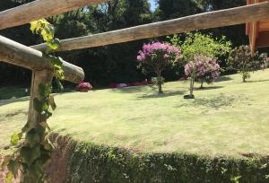 a wooden fence in a yard with trees and flowers at Villa Piccola Italia in Santo Antônio do Pinhal