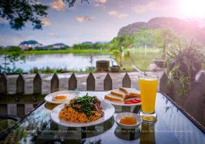 een tafel met twee borden eten en een glas sinaasappelsap bij Tam Coc Sunshine Homestay in Ninh Binh