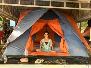 
a woman sitting in a tent under an umbrella at Coconutbeach Bungalows in Koh Rong Island
