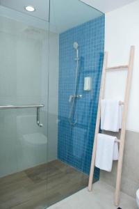 a bathroom with a glass shower with blue tiles at Bloo Bali Hotel in Legian