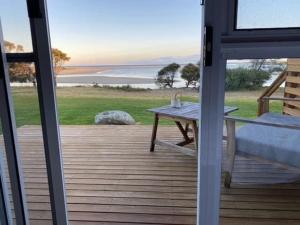 a patio with a table and a view of the ocean at Pelican Sands Scamander in Scamander