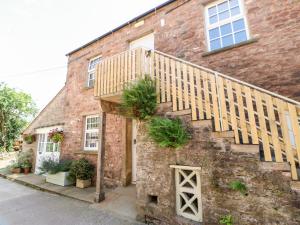 a brick house with a wooden staircase on it at Dairy Cottage in Kirkby Stephen