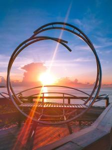 una vista de la puesta de sol a través de una escultura de metal en SeaRoad Homestay, en Taimali