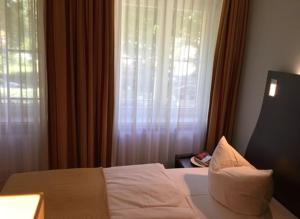a bedroom with a bed and a window with curtains at DämeritzSeehotel in Berlin +8 photos