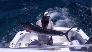 um homem segurando um peixe em um barco em Punta Cana Sol Caribe Beach Pool em Punta Cana
