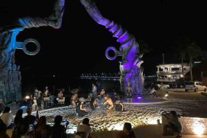 un grupo de personas sentadas alrededor de una fuente por la noche en Vive tus vacaciones, depa nuevo Playa del Carmen en Playa del Carmen