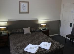 um quarto de hotel com uma cama com arcos brancos em City Motor Inn em Toowoomba