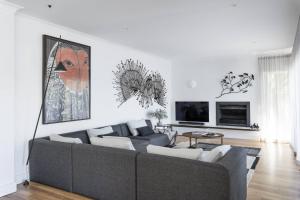 a living room with a gray couch and a tv at Calabash Bay Lodge in Berowra