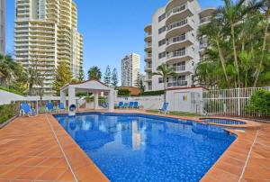 a swimming pool with blue chairs and buildings at The Ritz Resort Heated Pool in Gold Coast