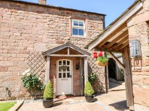 una vecchia casa in pietra con una porta bianca di The Cow Byre a Kirkby Stephen