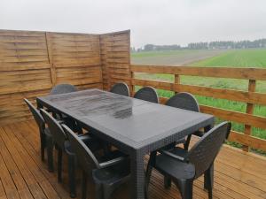 une table et des chaises noires sur une terrasse avec un champ dans l'établissement Gîte le parc Michel, à Roz-sur-Couesnon