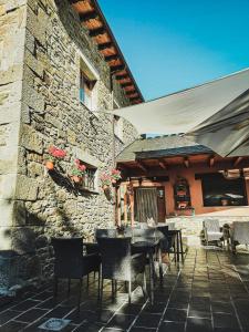 eine Terrasse mit Tischen und Stühlen und ein Steingebäude in der Unterkunft Hotel rural La Campanona in Villager de Laciana