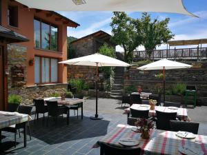 un patio con mesas, sillas y sombrillas en Hotel rural La Campanona, en Villager de Laciana