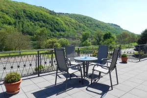 a table and chairs on a patio with a view of a river at Pension Mosella, Gästezimmer in Sankt Aldegund