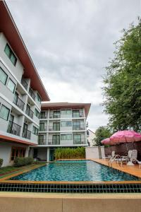 a hotel with a swimming pool in front of a building at Huen Jao Ban Hotel in Chiang Mai