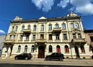 a large building with two cars parked in front of it at Glorious Apartment Near The Old City in Lviv