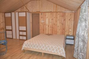- une chambre avec un lit dans une pièce dotée de murs en bois dans l'établissement Lola, à Ambrolaouri