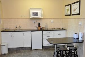 a kitchen with white cabinets and a table and a microwave at Birds of Paradise B&B in Eshowe