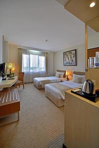 a hotel room with two beds and a desk at Grand Serela Setiabudhi Bandung in Bandung