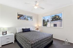 a bedroom with a bed and two windows at Tin Can Bay Tourist Park in Tin Can Bay