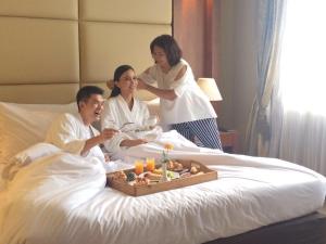 a group of people sitting in a bed with a tray of food at Grand Serela Setiabudhi Bandung in Bandung