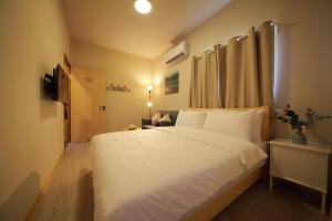 ein Schlafzimmer mit einem großen Bett mit weißer Bettwäsche in der Unterkunft 海邊小屋 in Green Island