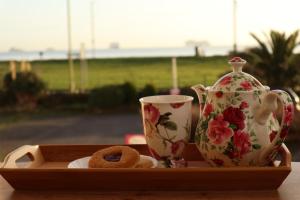 een dienblad met twee kopjes en een donut en een theepot bij Cherry Tree Hotel in Paignton