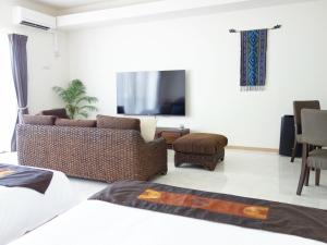 a living room with a couch and a tv at サンライン北谷コンドミニアムリゾート in Chatan