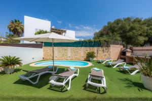 a group of chairs and an umbrella and a swimming pool at Nikydan in Cala d´Or