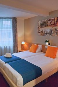 a hotel room with two beds with orange and blue sheets at Vincents Bed&Bistro in Etten-Leur