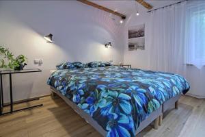 a bedroom with a large bed with a blue floral bedspread at Pokoje i apartamenty przy Sosnowej in Poddąbie