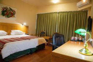 a hotel room with a bed and a desk with a lamp at BON Hotel Bloemfontein Central in Bloemfontein