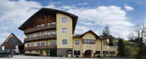 un grand bâtiment jaune avec un toit en gambrel dans l'établissement Landhotel Oberwengerhof, à Spital am Pyhrn