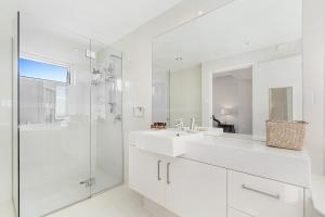 een witte badkamer met een wastafel en een douche bij Silver Sapphire on Sixth Penthouse in Maroochydore