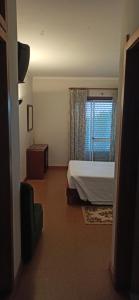 a hotel room with a bed and a window at Pensão Continental Machado in Caldelas +11 photos