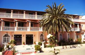 a large building with a palm tree in front of it at Alkion Hotel in Sidari