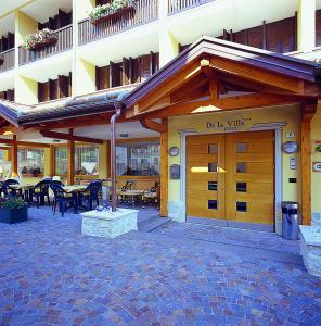 - un bâtiment avec une porte en bois, des tables et des chaises dans l'établissement Hotel De la Ville, à Andalo