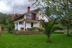 una casa con una palma di fronte di Casa Las Lindes Valle de Cabuerniga , Cantabria a Cabuérniga