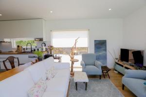 a living room with a white couch and a kitchen at Like-home-T2 house, pool, AC, garden in Ericeira